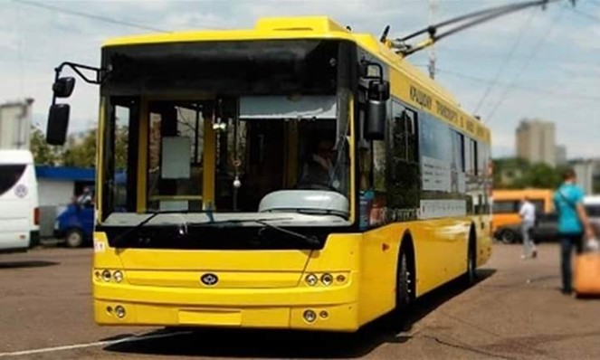 Сучасний жовтий тролейбус Богдан стоїть на зупинці або на території депо у світлу пору доби.